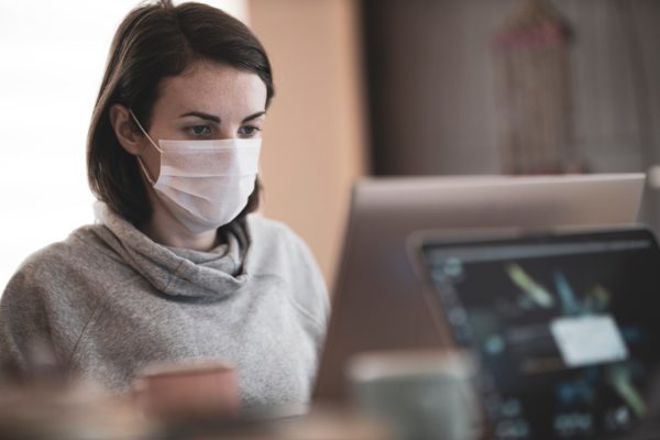 Woman wearing mask using computer